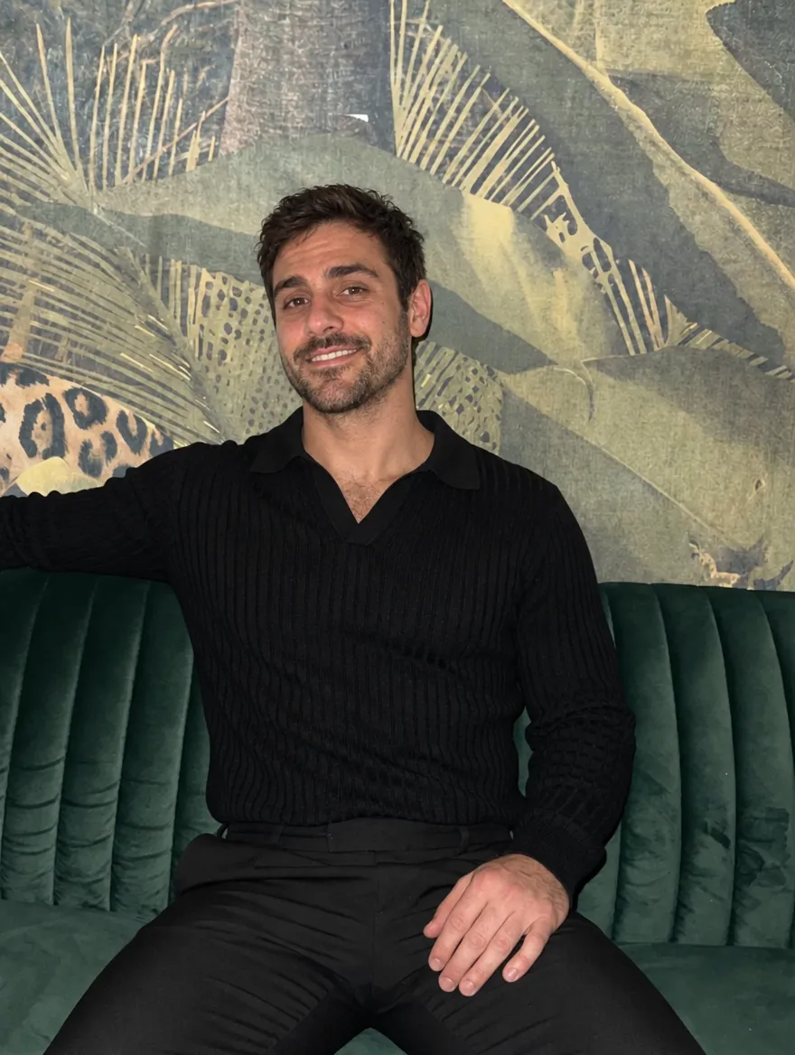 AI dating photo of Chris in a black polo on a velvet sofa
